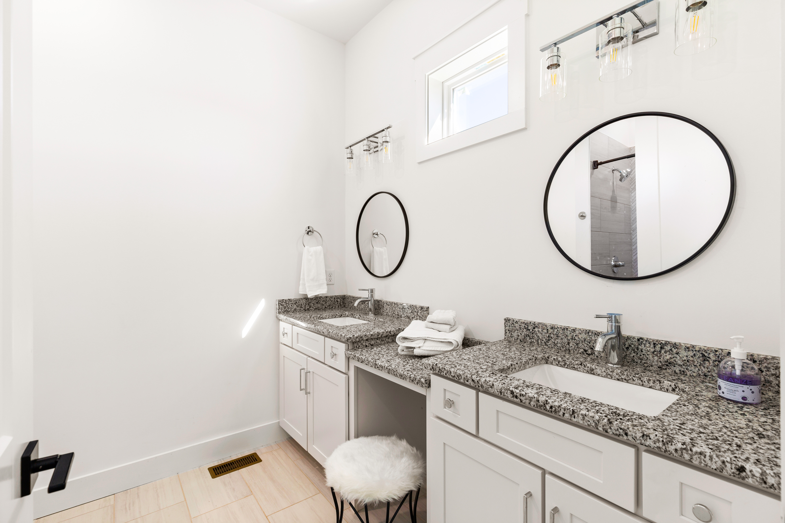 Modern bathroom with dual vanity, round mirrors, and granite countertops